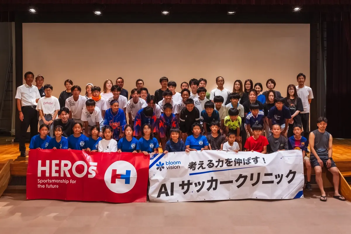 AIサッカークリニックの横断幕を持つ参加者と保護者の集合写真（壱岐市・屋内会場）