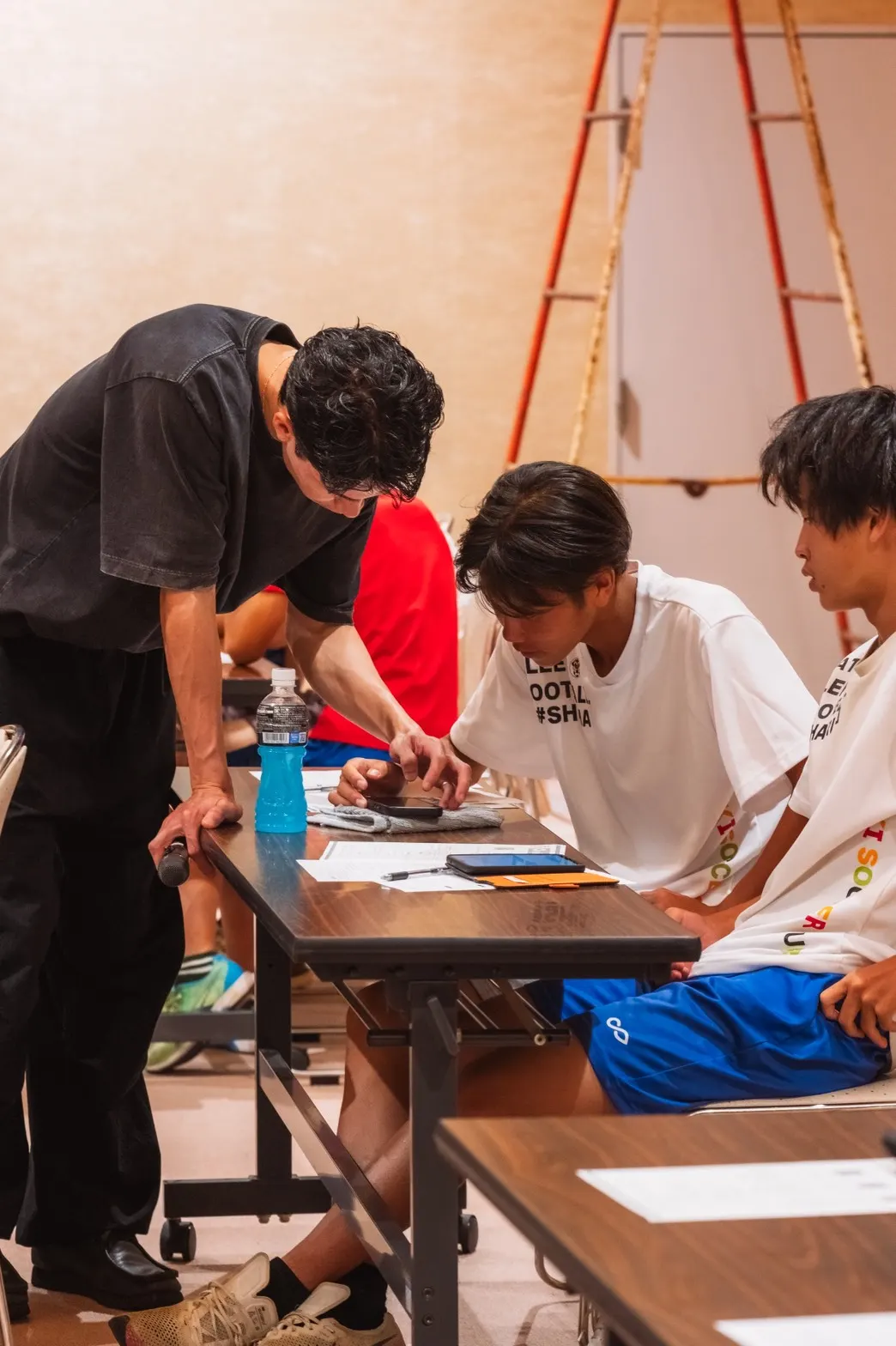 タブレットを使う中学生にスタッフが操作を説明する様子